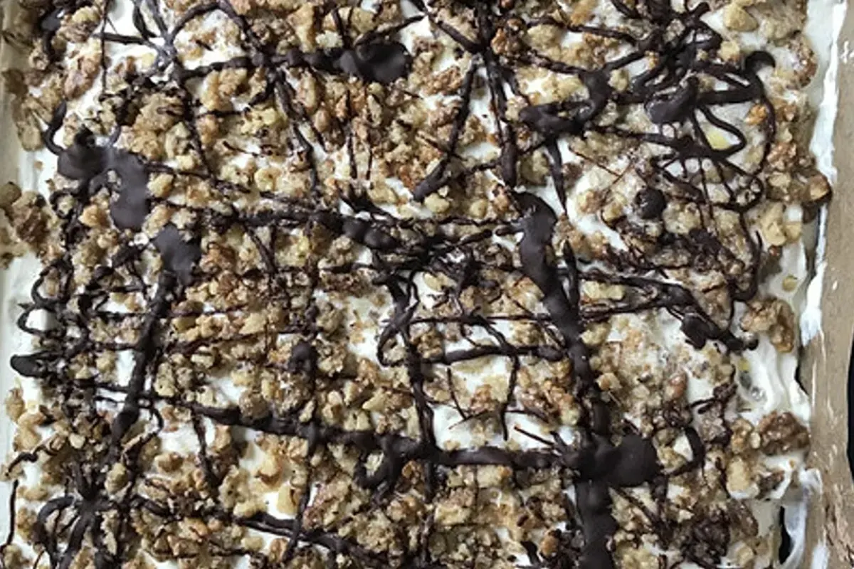 Saftiger Nuss‑Schoko‑Kuchen mit glänzender Schokoglasur und gerösteten Walnüssen, kunstvoll auf einem Holzbrett angerichtet