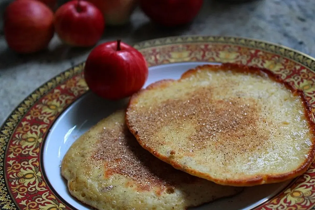 Goldbraune belgische Pfannkuchen mit geriebenen Äpfeln und Zimtzucker, angerichtet auf einem rustikalen Holzbrett