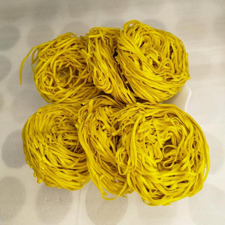 Mengocok mie kuning dalam keranjang anyaman
