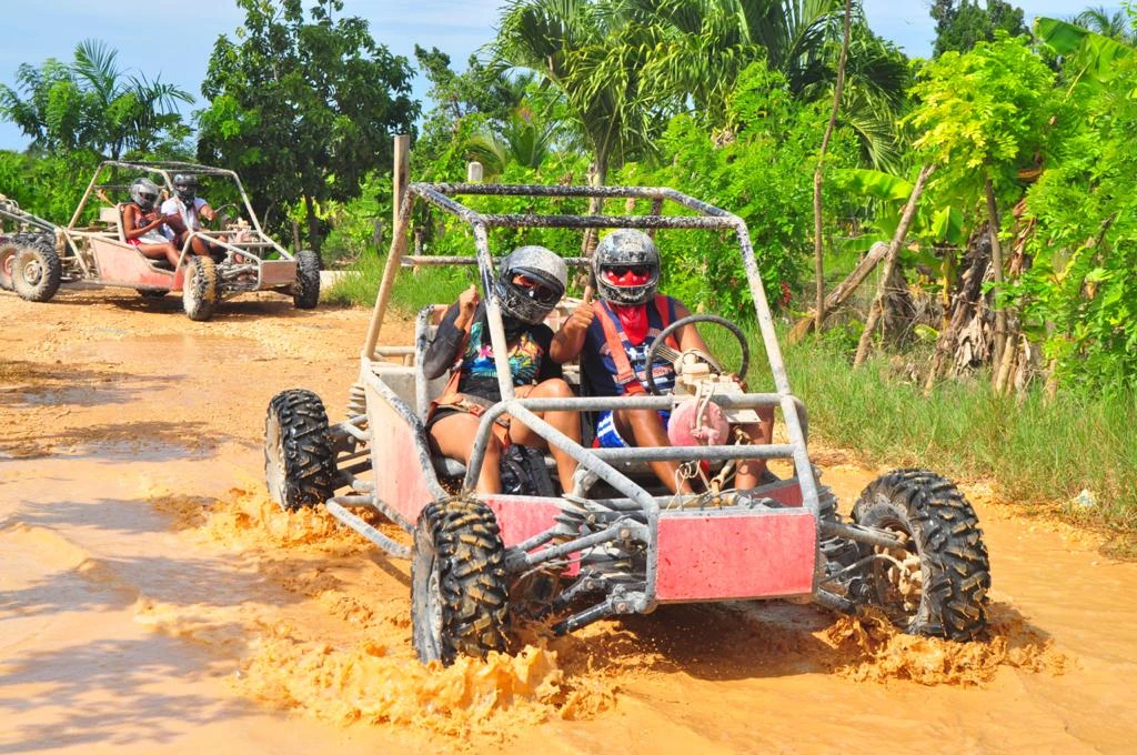 A close-up of a muddy off-road buggy parked on a tropical trail
