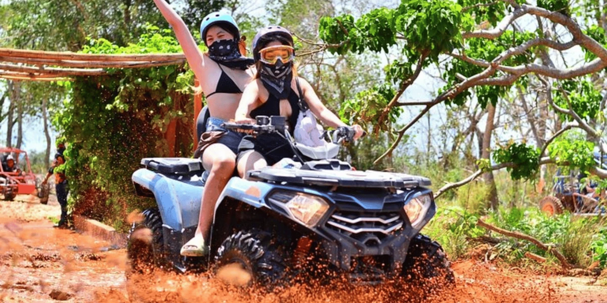 A traveler wearing a bandana and sunglasses covered in mud after a buggy ride
