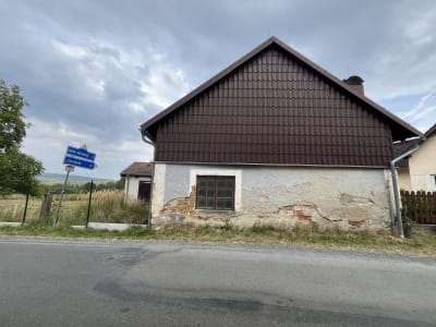 Pohled na stodolu č.p.12 z ulice s patrnými fragmenty zdiva z vepřovic v místě opadané omítky