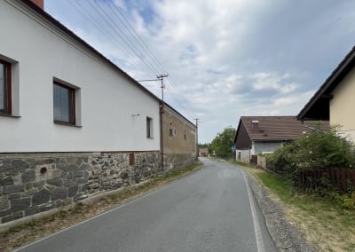 Širší vztahy - uliční pohled severním směrem, vlevo je stodola č.p. 14, vpravo přes ulici stodola č.p. 12 s obdobnou technologií smíšeného zdiva s vepřovicemi