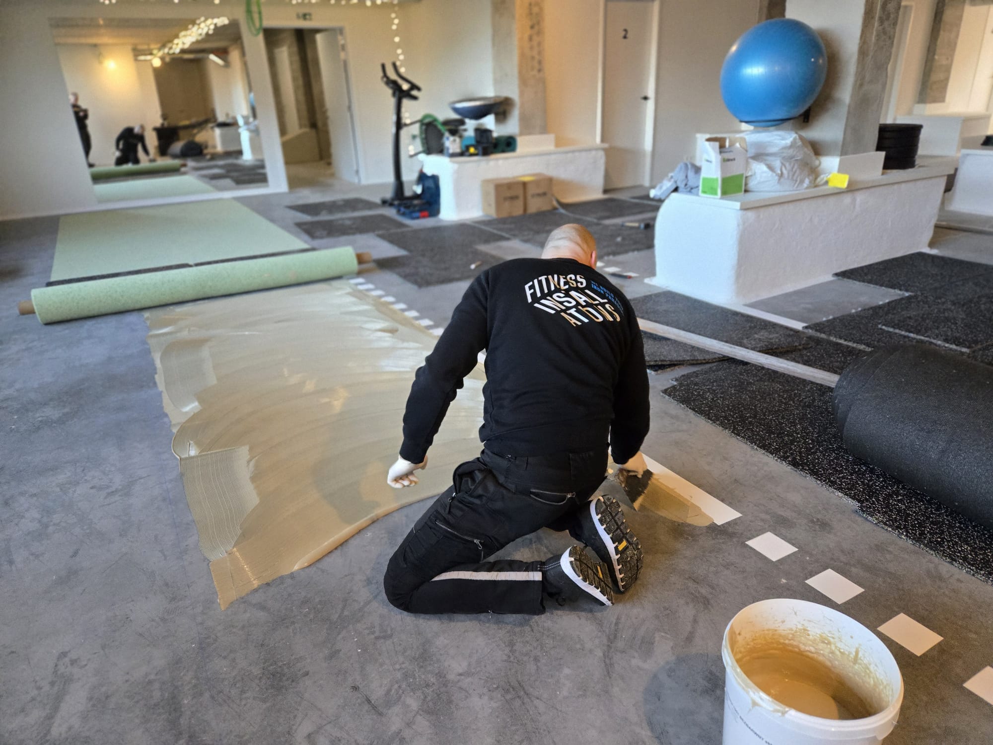 Monteur legt een vloer in een fitnessruimte
