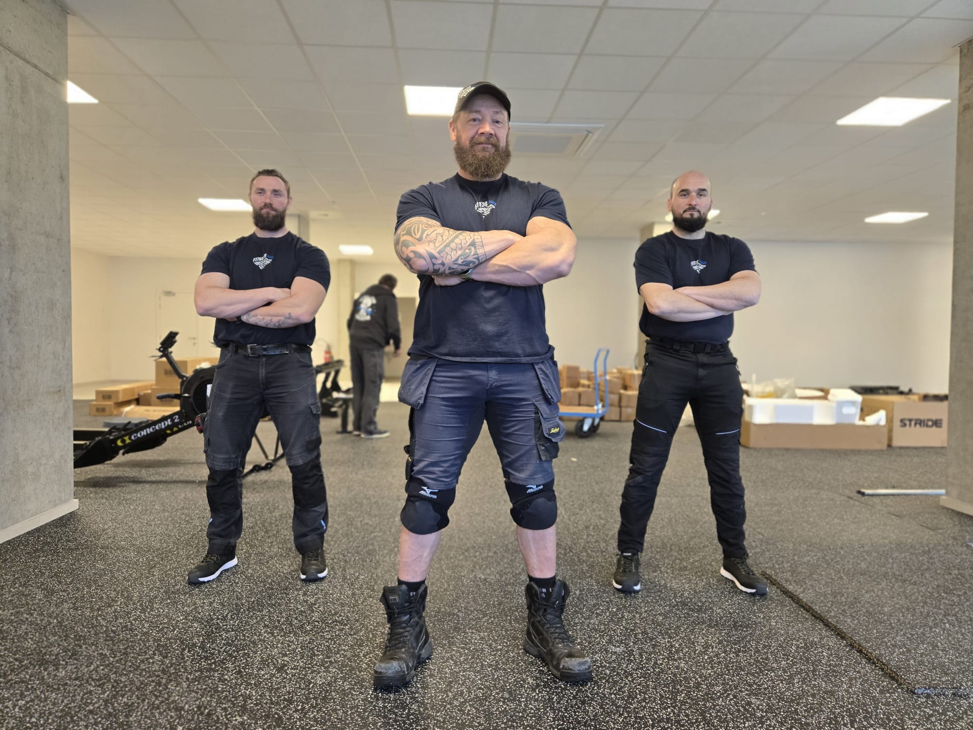 Drie monteurs van Fitness Installations poseren in een fitnessruimte