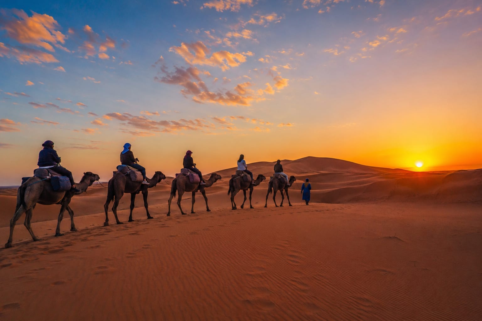 Family riding camels in Merzouga Sahara Desert