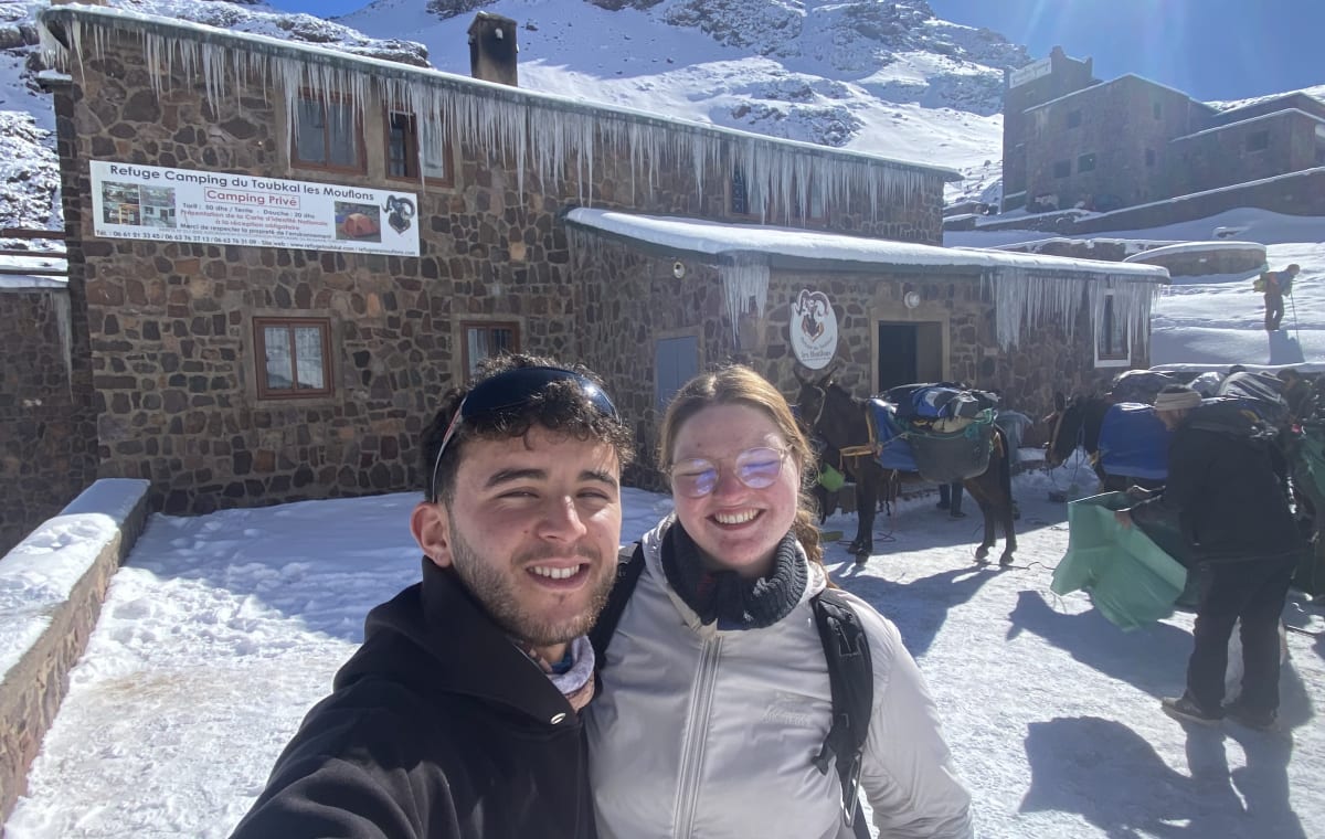 Youssef taking a selfie with a client from Norway in front of Toubkal Refuge Les Mouflons in the High Atlas Mountains