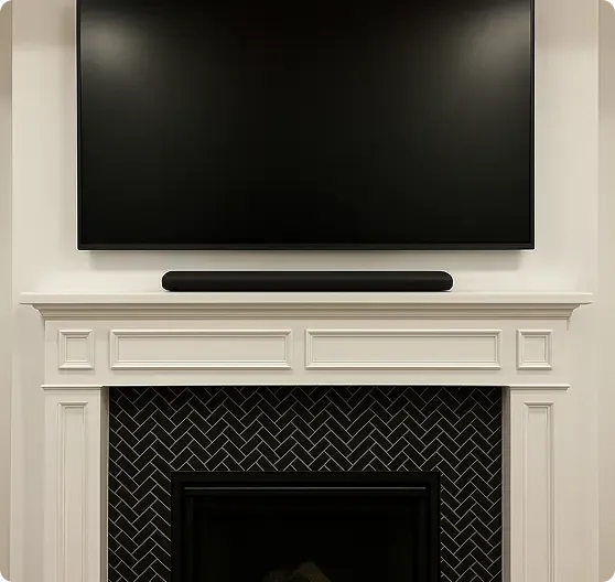 A flat-screen TV and soundbar are mounted above a white fireplace with a black herringbone tile pattern inside the opening.