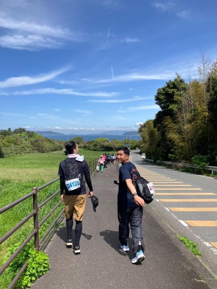 糸島の海沿いの道を歩くチームメンバー