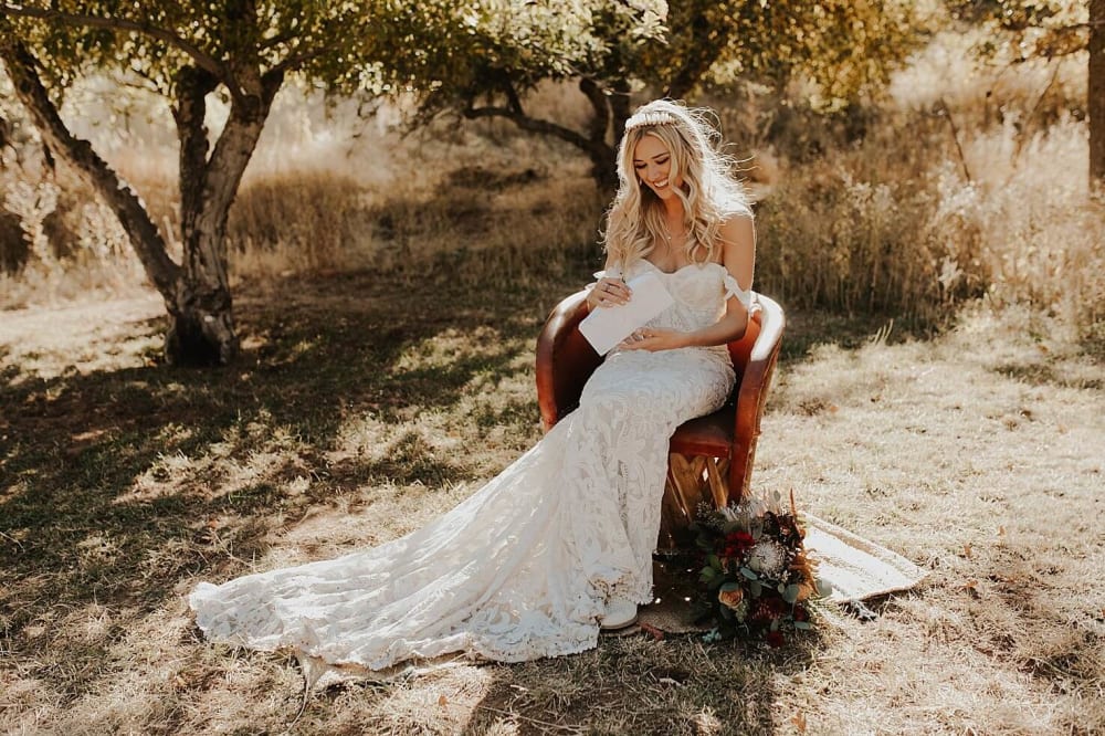 Bride sitting on a chair, reading a letter from the groom