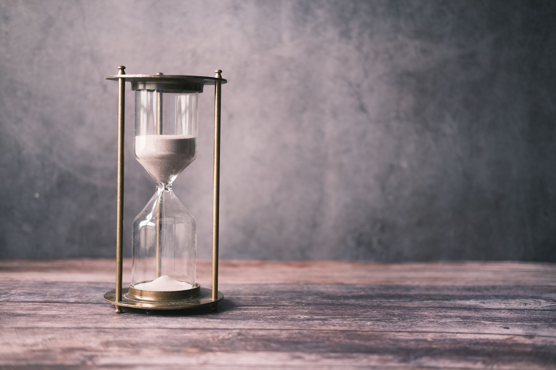 Reloj de arena de latón sobre madera, la arena cayendo