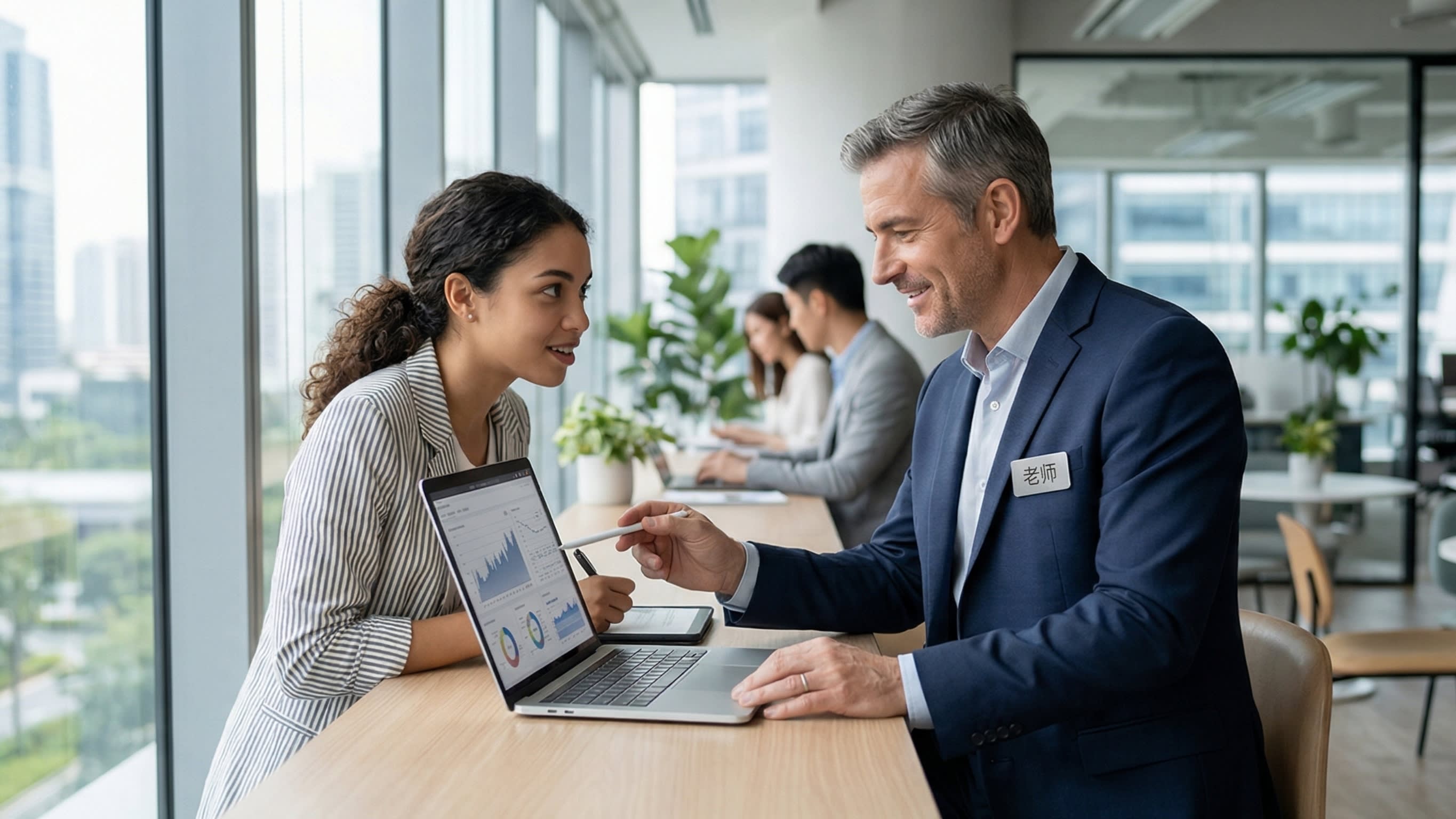 A bright, professional corporate photography shot. A junior employee is respectfully consulting with a senior, experienced colleague over a laptop. The dynamic illustrates the modern workplace use of the title 'Laoshi' (Teacher/Mentor) to show deep professional respect.
