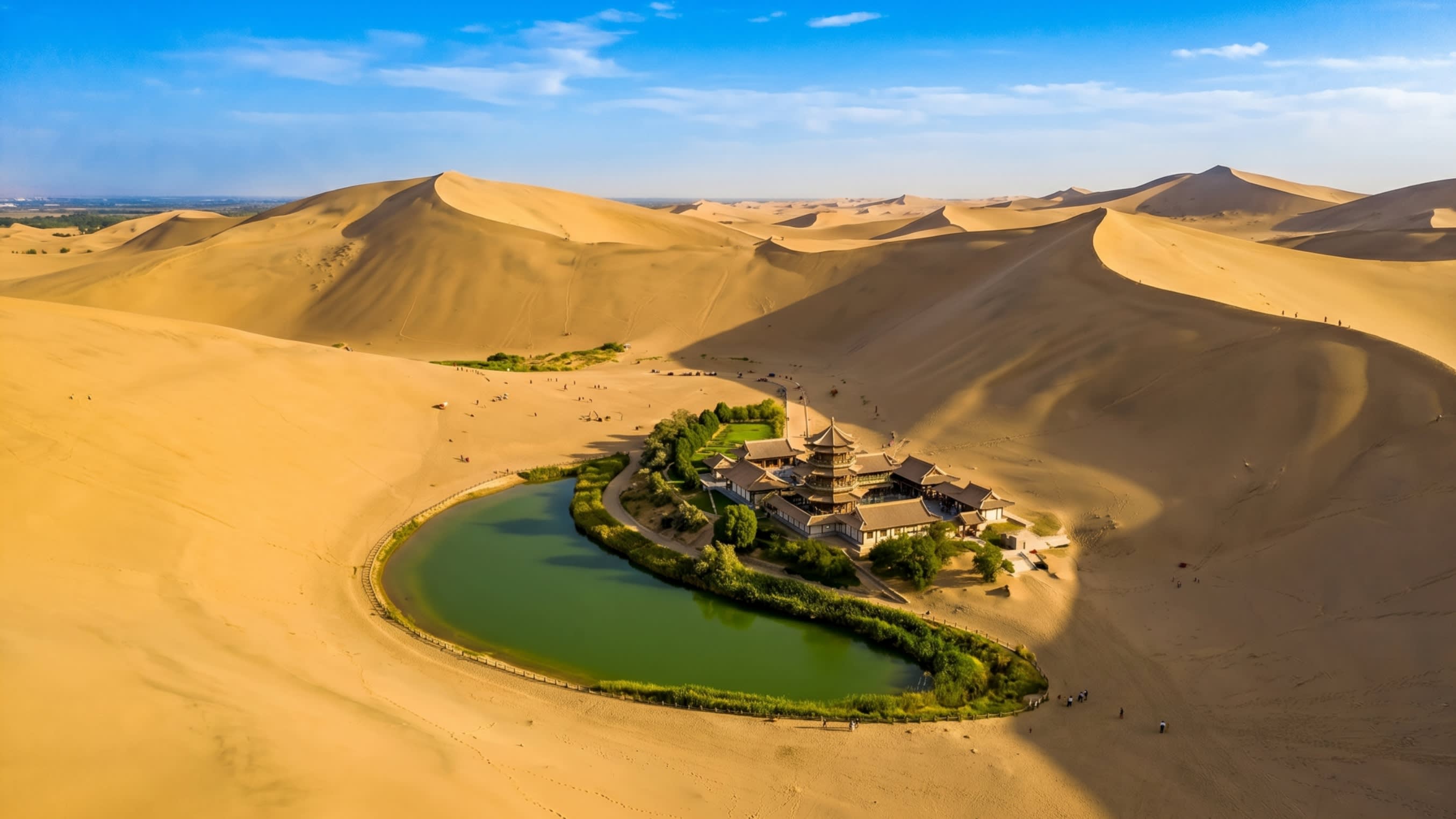 Image 2 - The emerald Crescent Moon Spring oasis surrounded by towering sand dunes