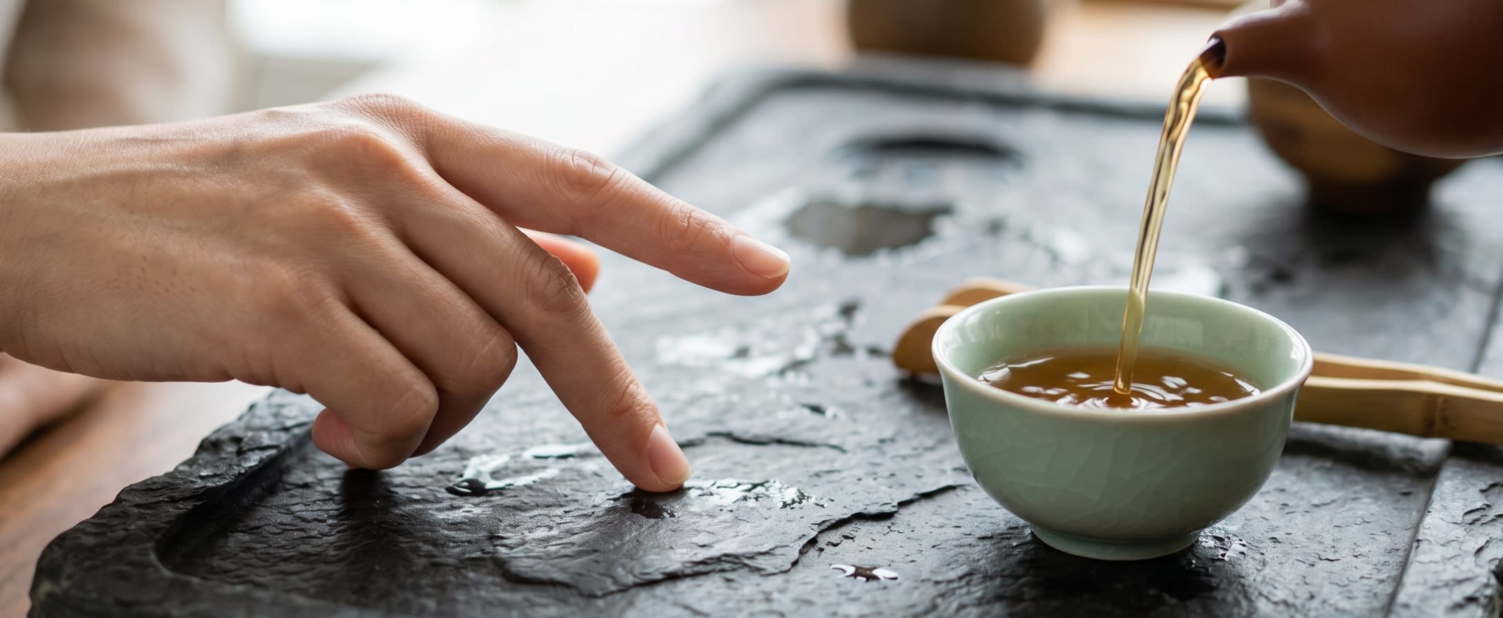 A close-up of a tea ceremony where fingers are gently tapping on a wooden table to show appreciation