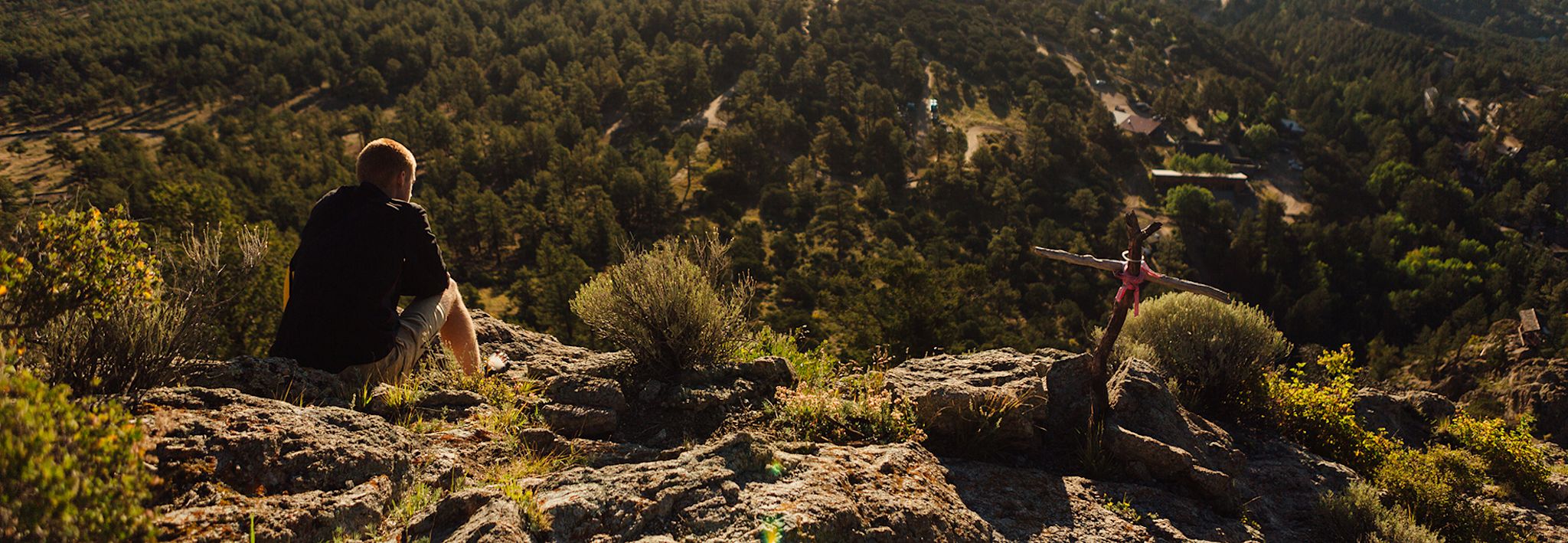 CCU student sitting in the mountains looking out at beautiful Colorado.