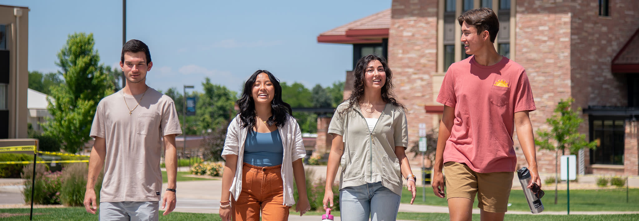 four students outside walking and talking on campus