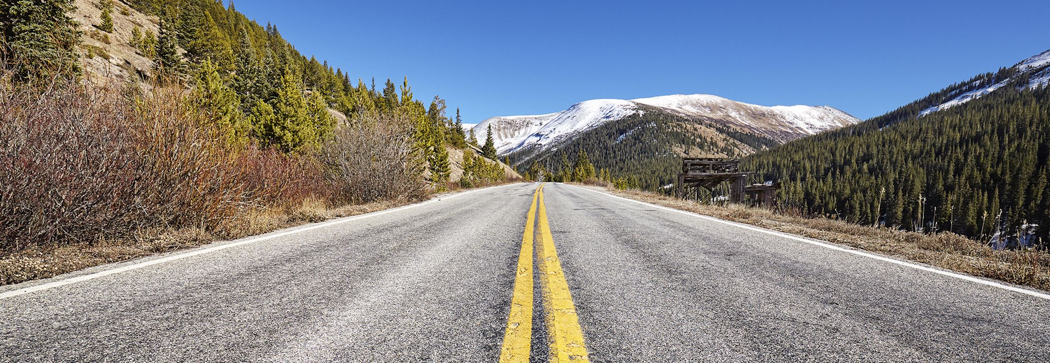 A road in the mountains leads to a snowy peak in Colorado.