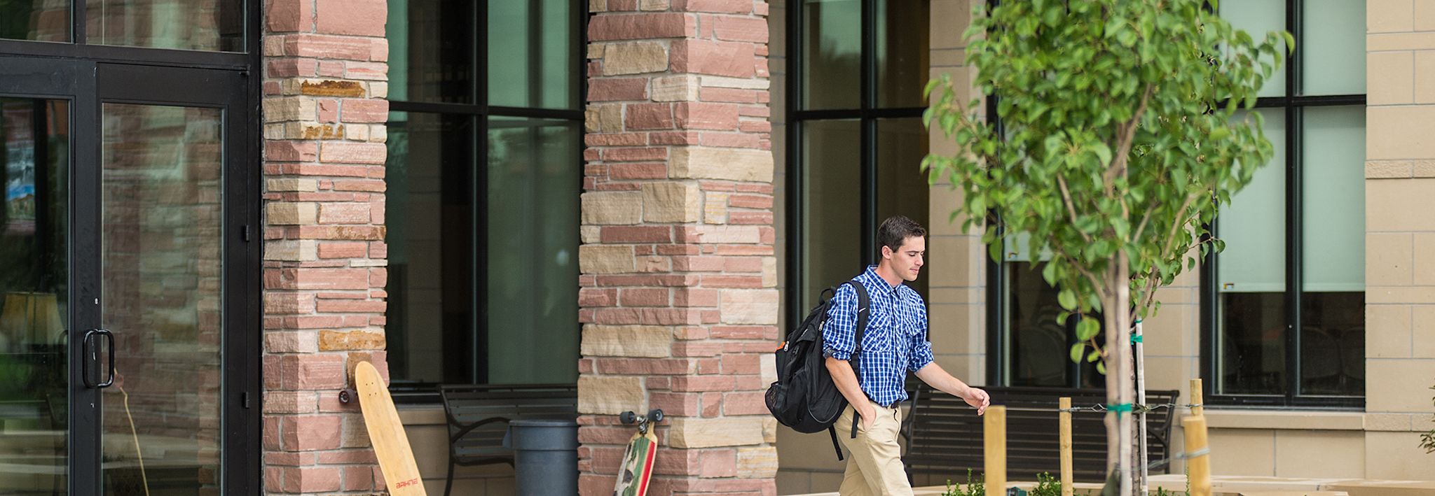 A male student is walking outside of Leprino Hall at CCU.