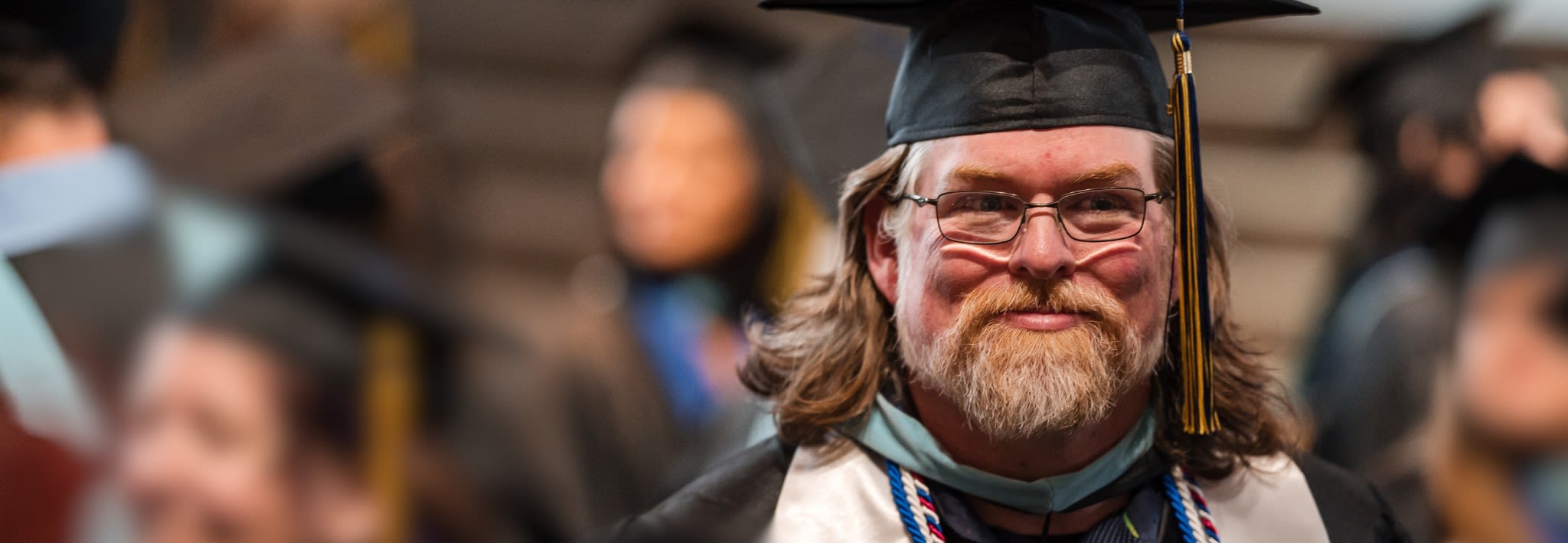 adult male graduate smiling at commencement