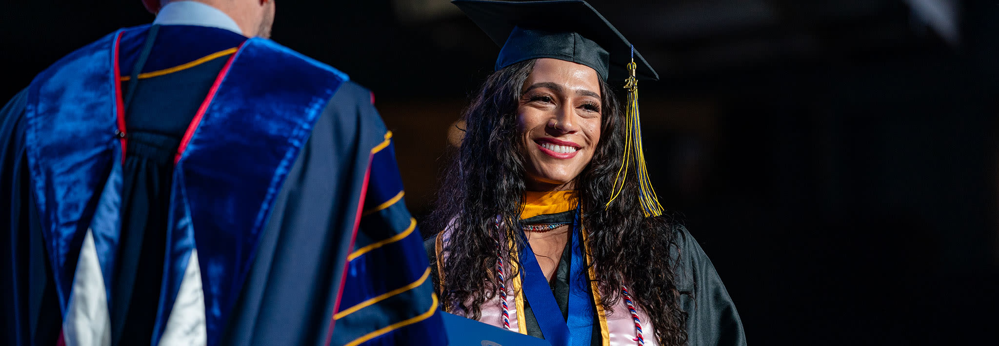 smiling ccu online graduate accepting her diploma