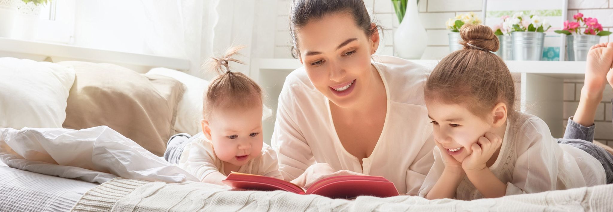 A young mother is reading a book to her two daughters.