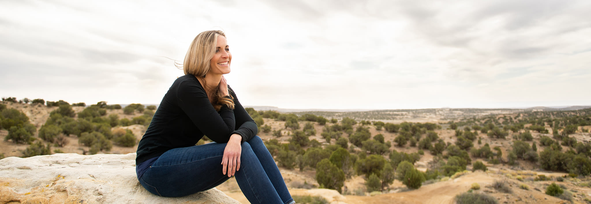 CCU Online students sitting on a rock in desert setting looking into the distance