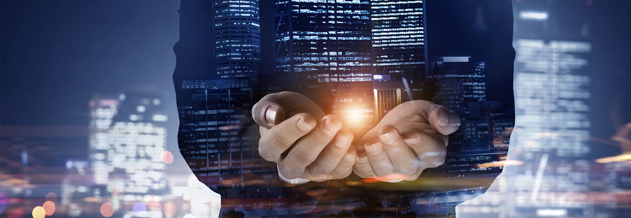 A businessman at work A man is holding out his hands in front of downtown buildings.