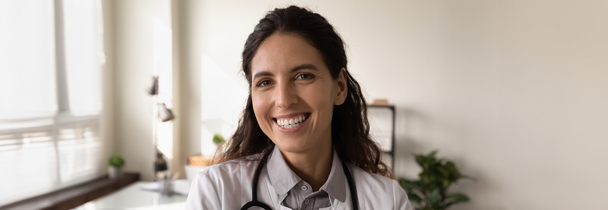 nursing student in uniform smiling against a grey background