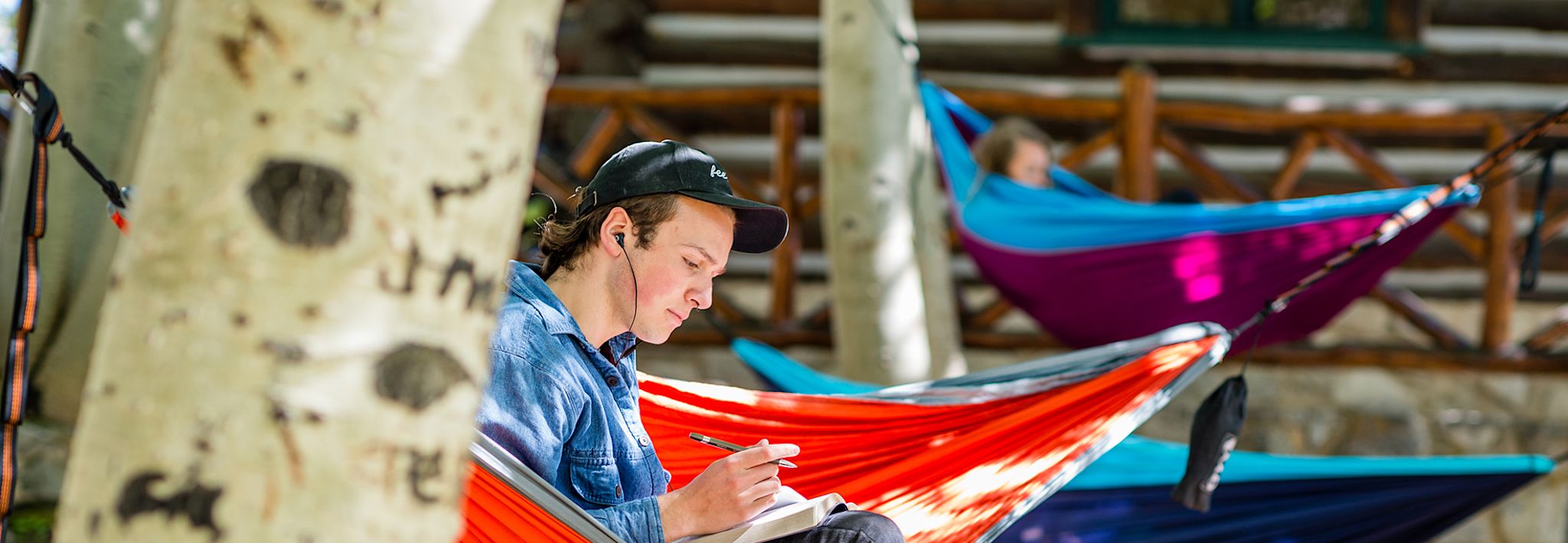 CCU student doing homework in a hammock on a nice, sunny day.