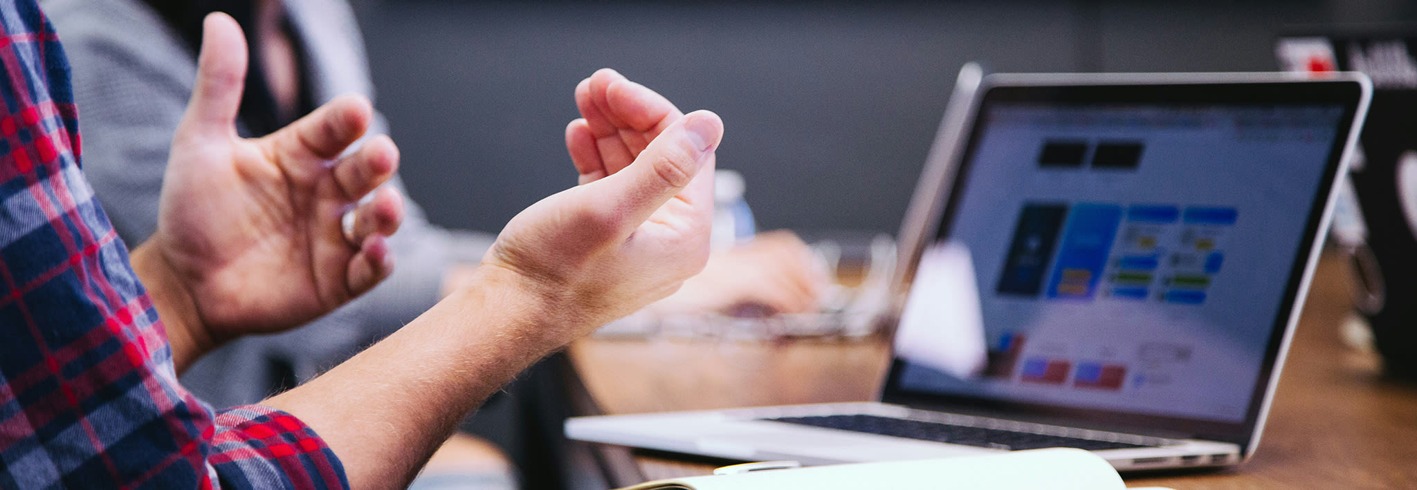 male student sitting by laptop with his hands gesturing in the air