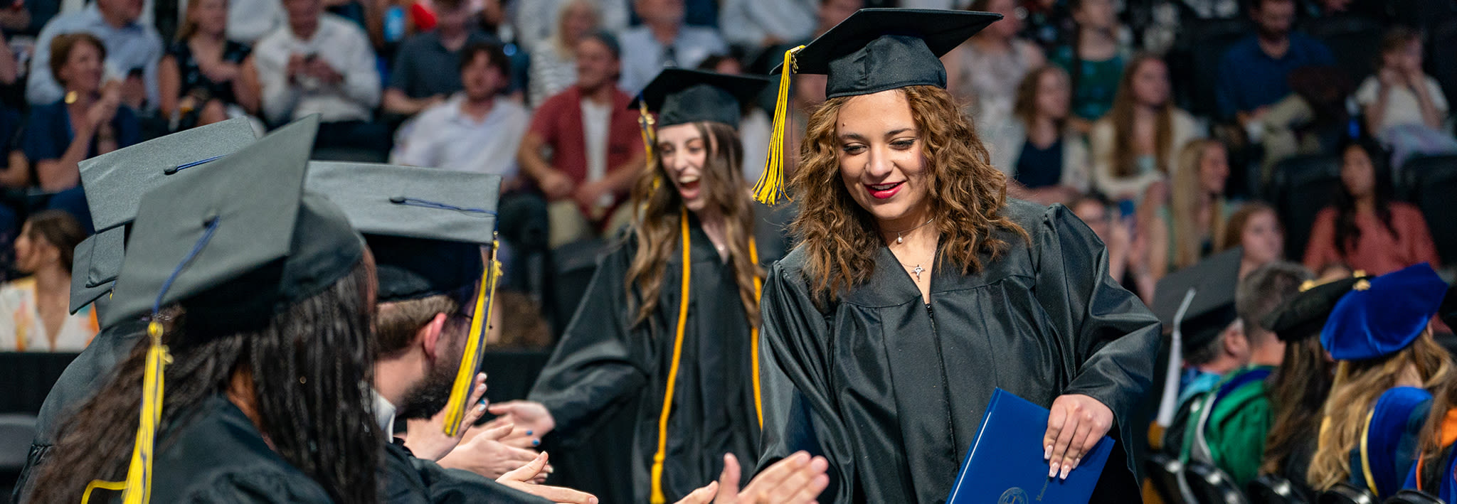 CCU graduate high-fiving other graduates at commencement 2025