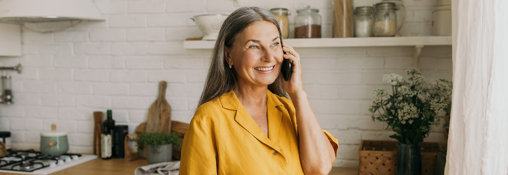 smiling retired woman talking on the phone in her kitchen