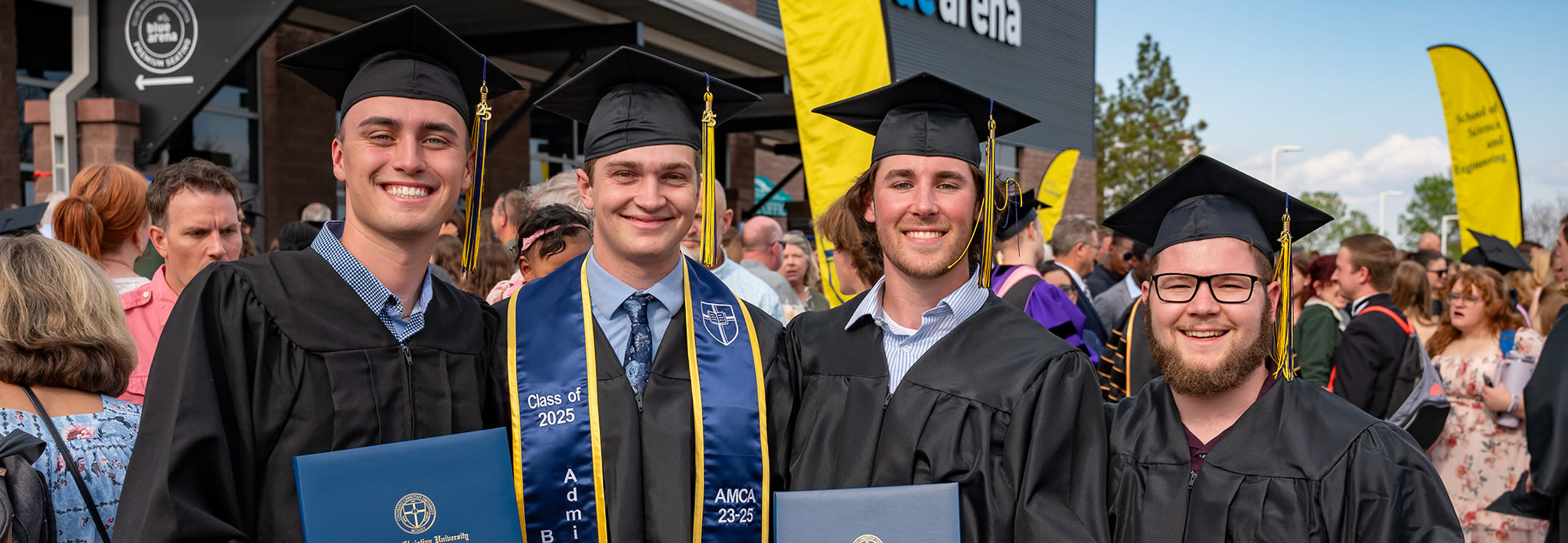 group of ccu graduates smiling and gathering outside at graduation
