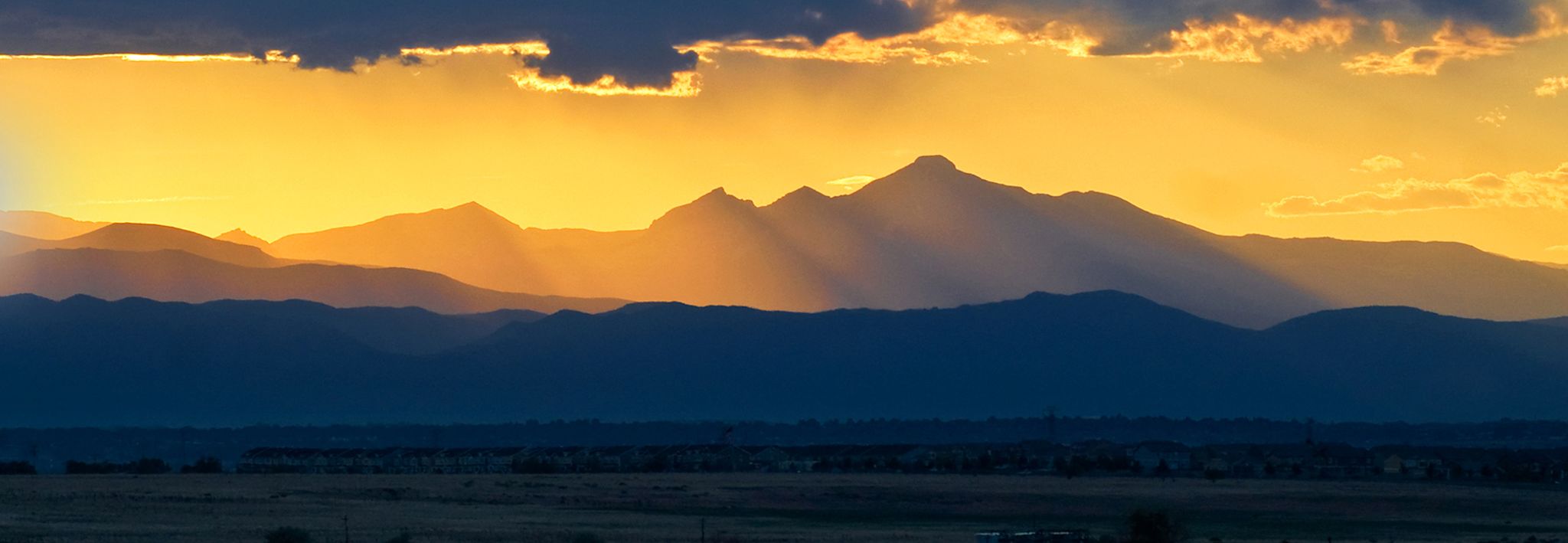 Front range mountains with gold sunlight shining down on it. 