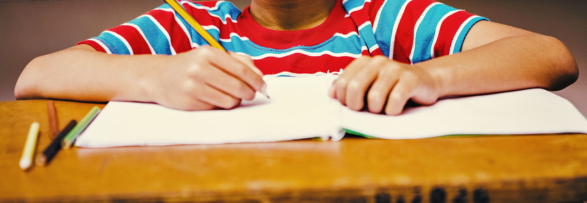 A child writing in his school notebook. 