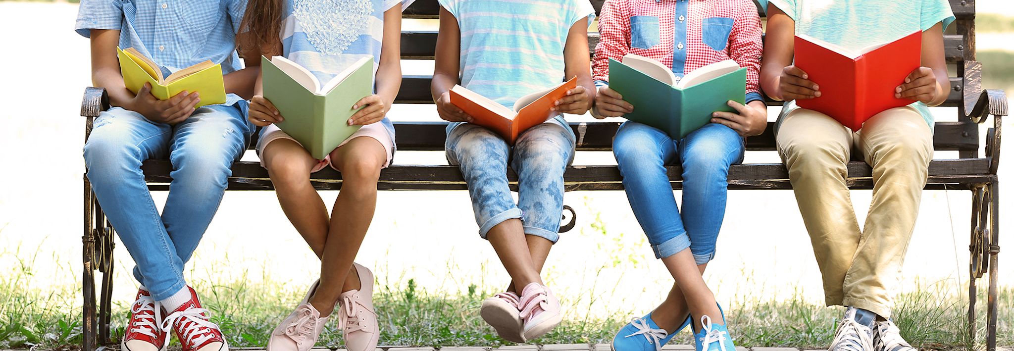 Kids reading Kids posing for a cute picture on a bench with their books.