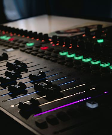soundboard with faders and green lit up buttons