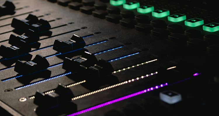 soundboard with faders and green lit up buttons