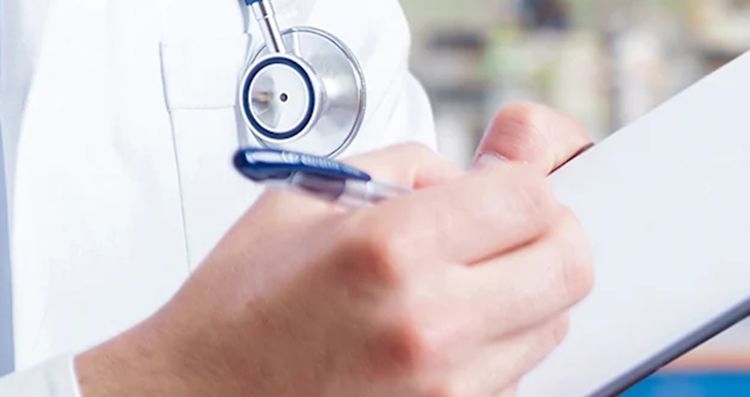 doctor in a lab coat writing on a clipboard
