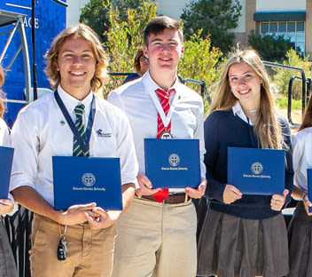 two high school students holding diplomas