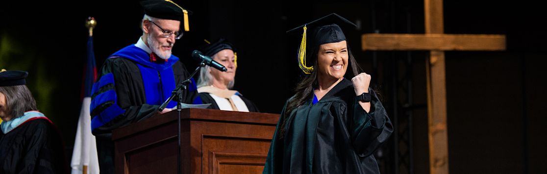 ccu online student cheering as she receives her diploma at commencement (slide 1 of 6)