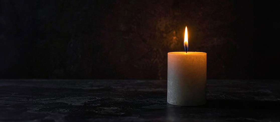 lit candle against a plain and dark background
