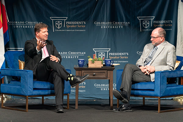 Description of this image. Jeremy S. Adams speaking with President Hogue