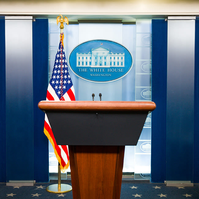 white house podium with american flag behind