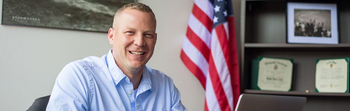 male ccu online military student smiling while working on a laptop (slide 3 of 7)
