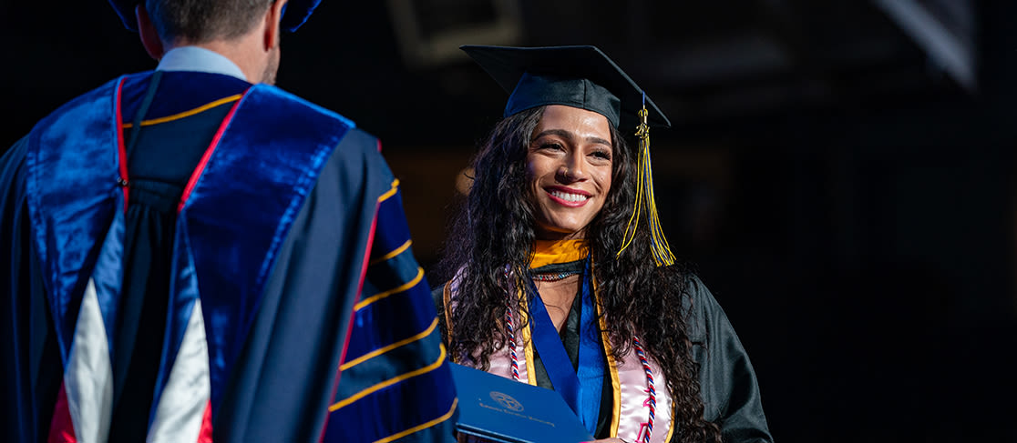 Student smiles as she receives her diploma