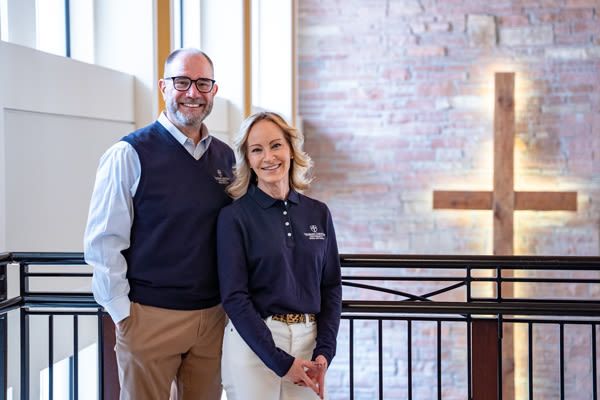 president eric hogue and first lady tammy with a cross behind them