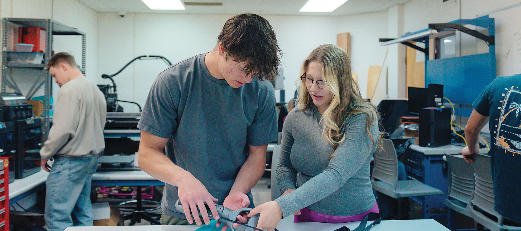 engineering staff and students with bionic arm in classroom