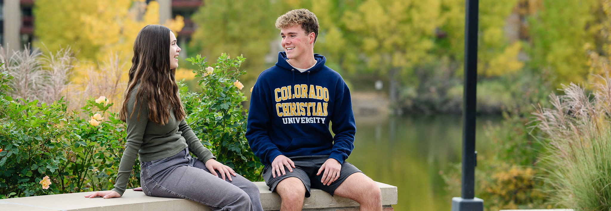 students sitting on a brick wall talking