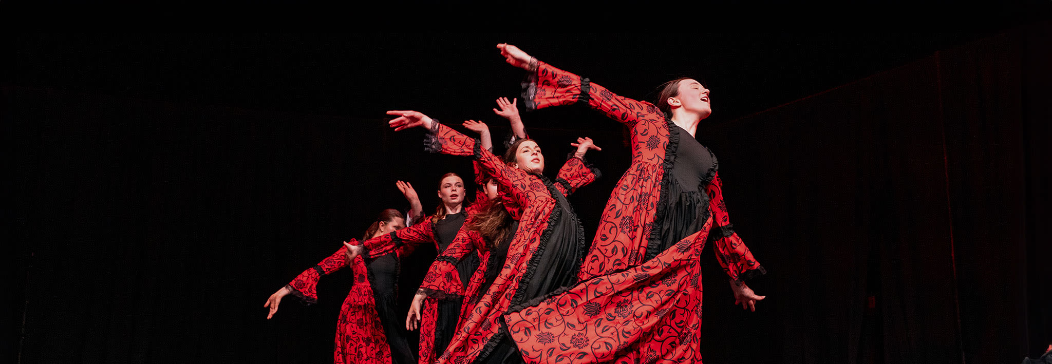 dancers dressed in red and black fanning out on the stage